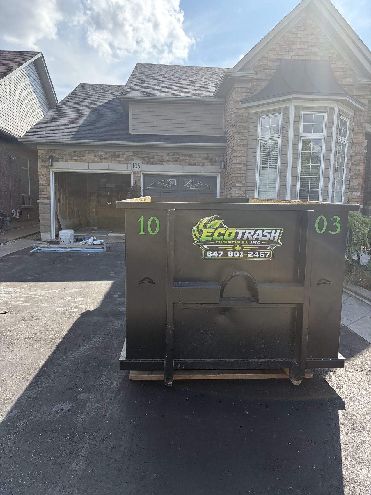A clean black Eco Trash 10 yard disposal bin placed on a residential driveway