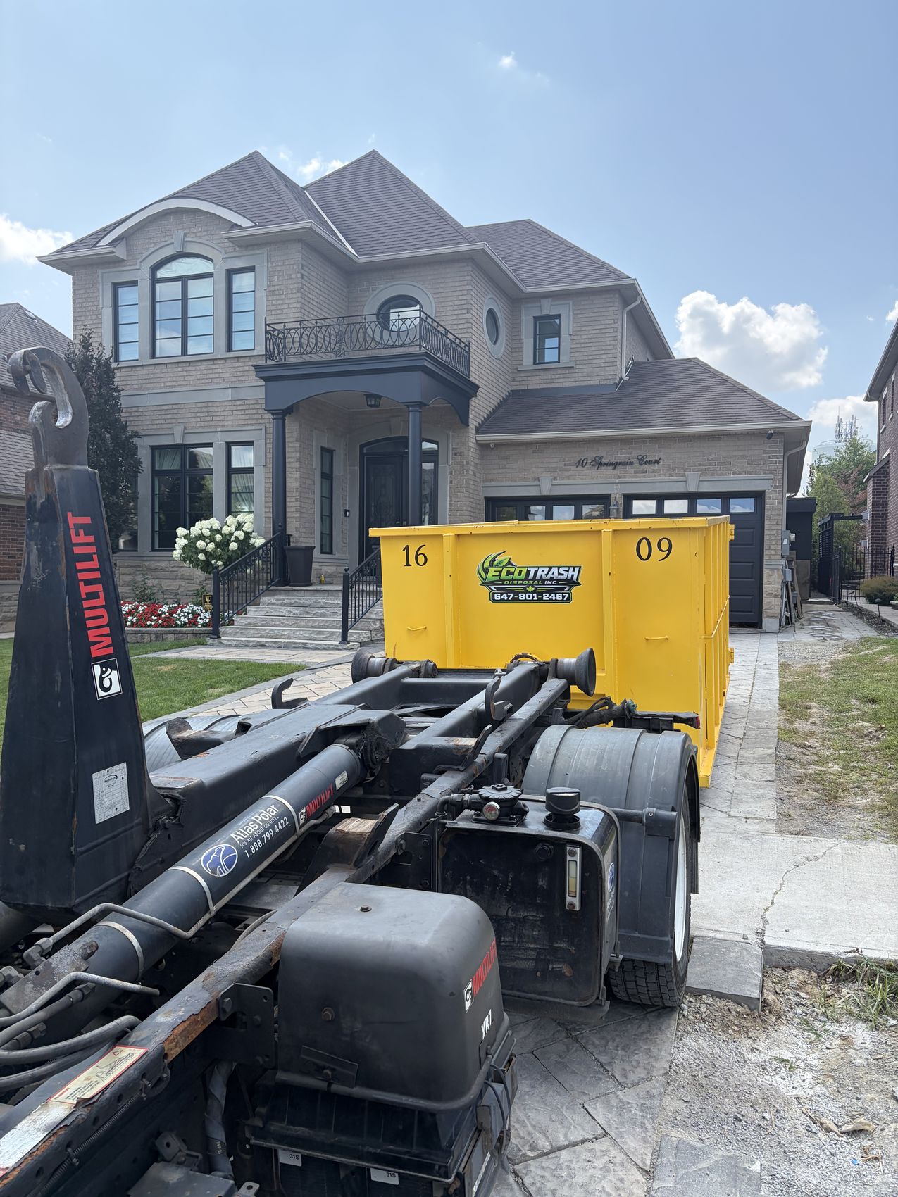 A 16 yard Eco Trash bin in front of a large home