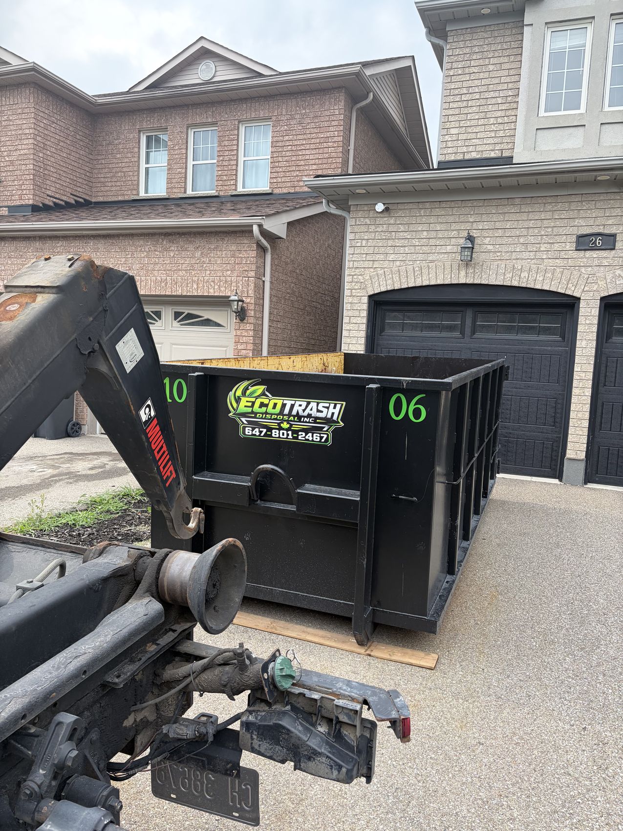 Close view of an Eco Trash bin being positioned by the hook lift arm