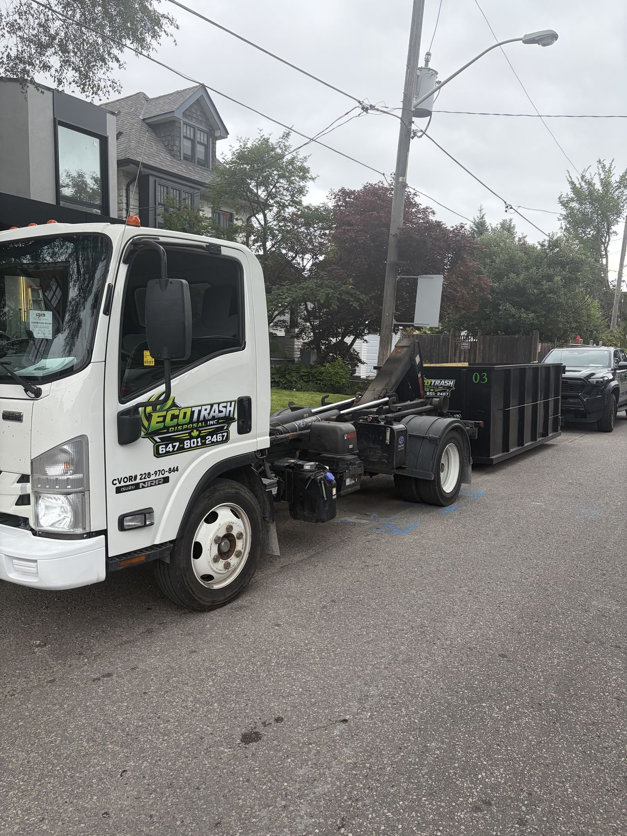 Eco Trash truck collecting a bin on a narrow city street
