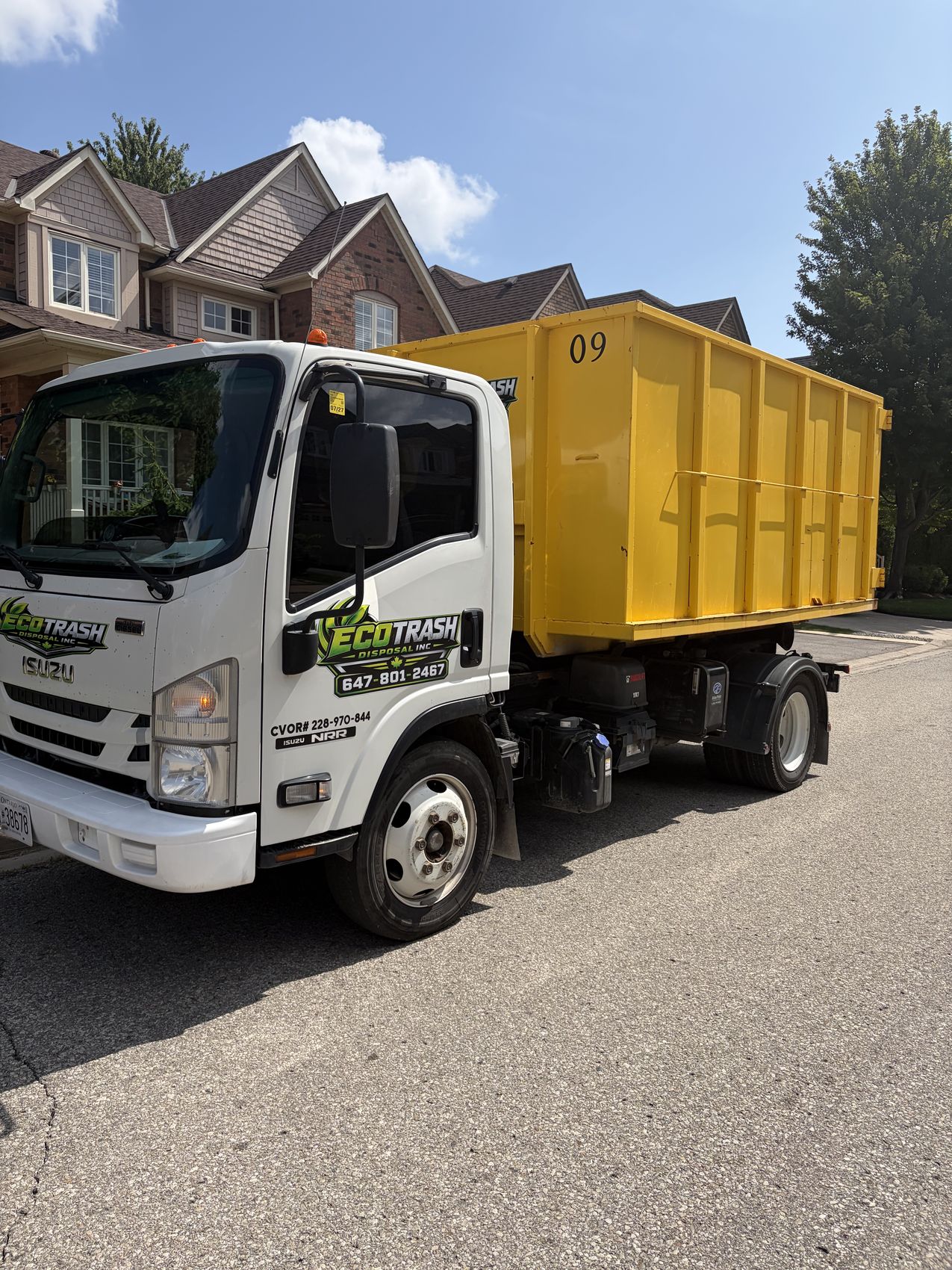 Eco Trash truck carrying a loaded bin under a blue sky