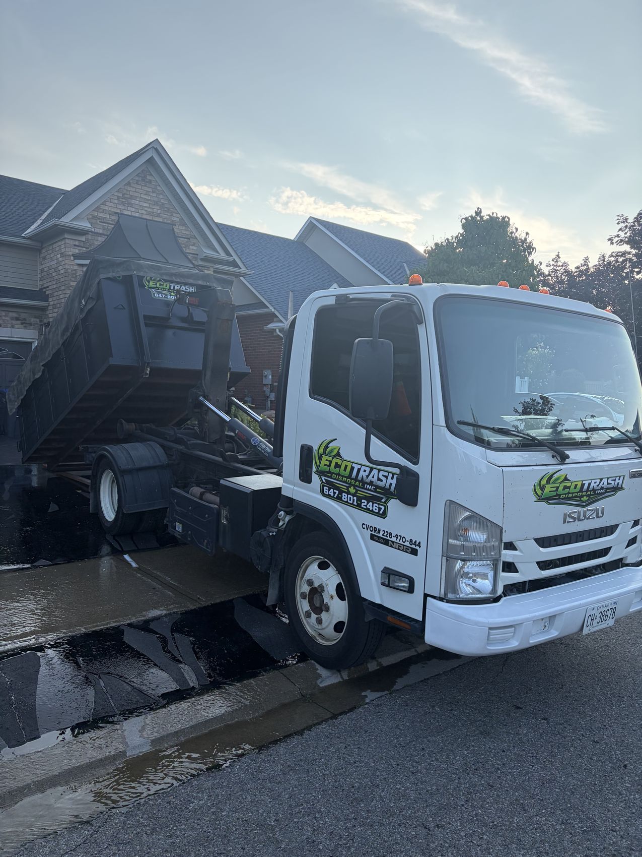Eco Trash hook lift truck loading a bin onto the deck